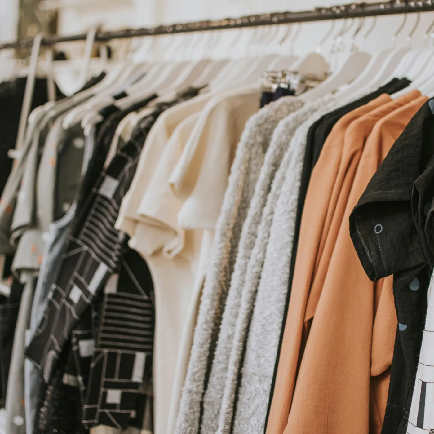 Perchero con remeras, buzos y camisas en negro, gris, crudo y terracota