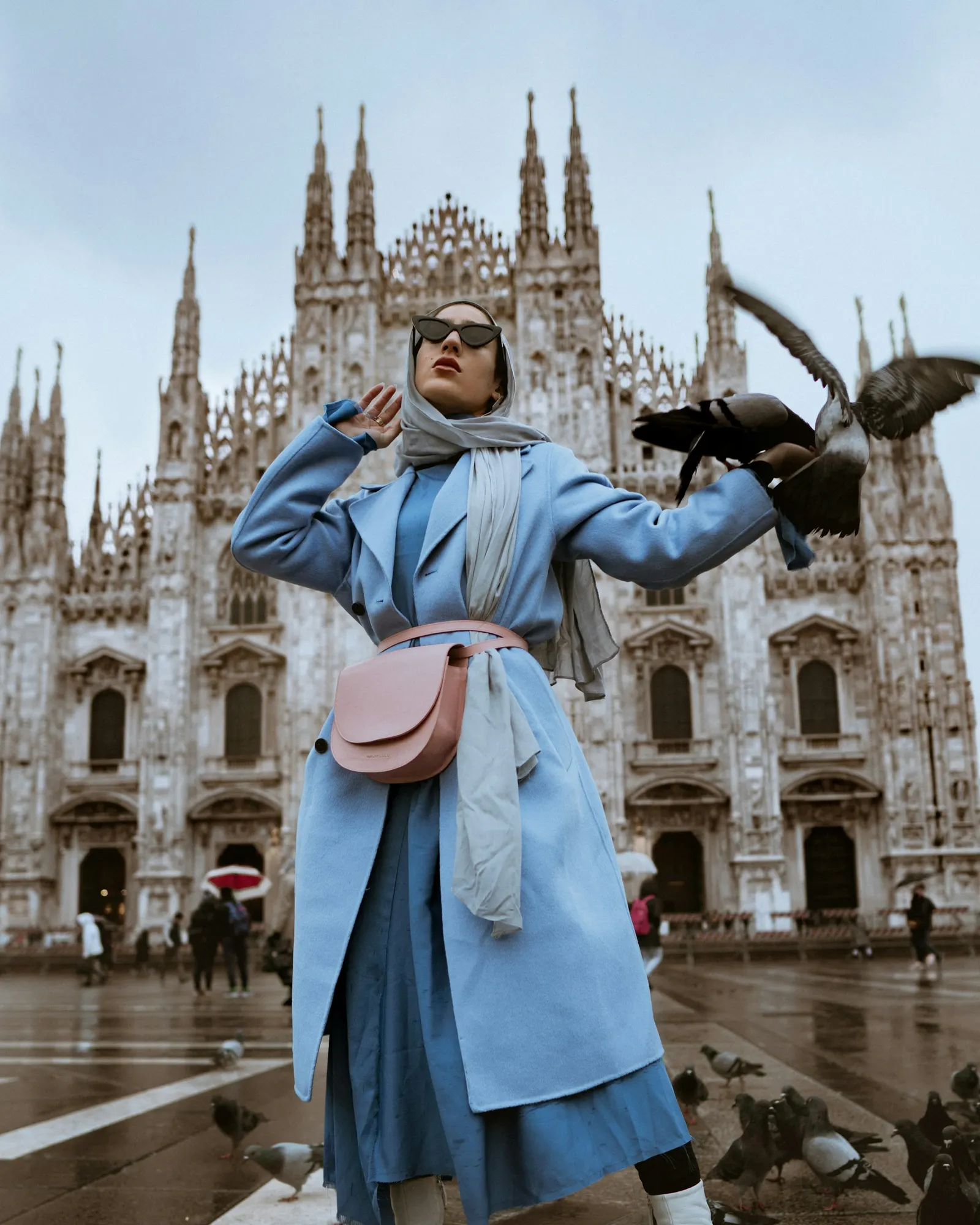 mujer con tapado celeste frente a una catedral