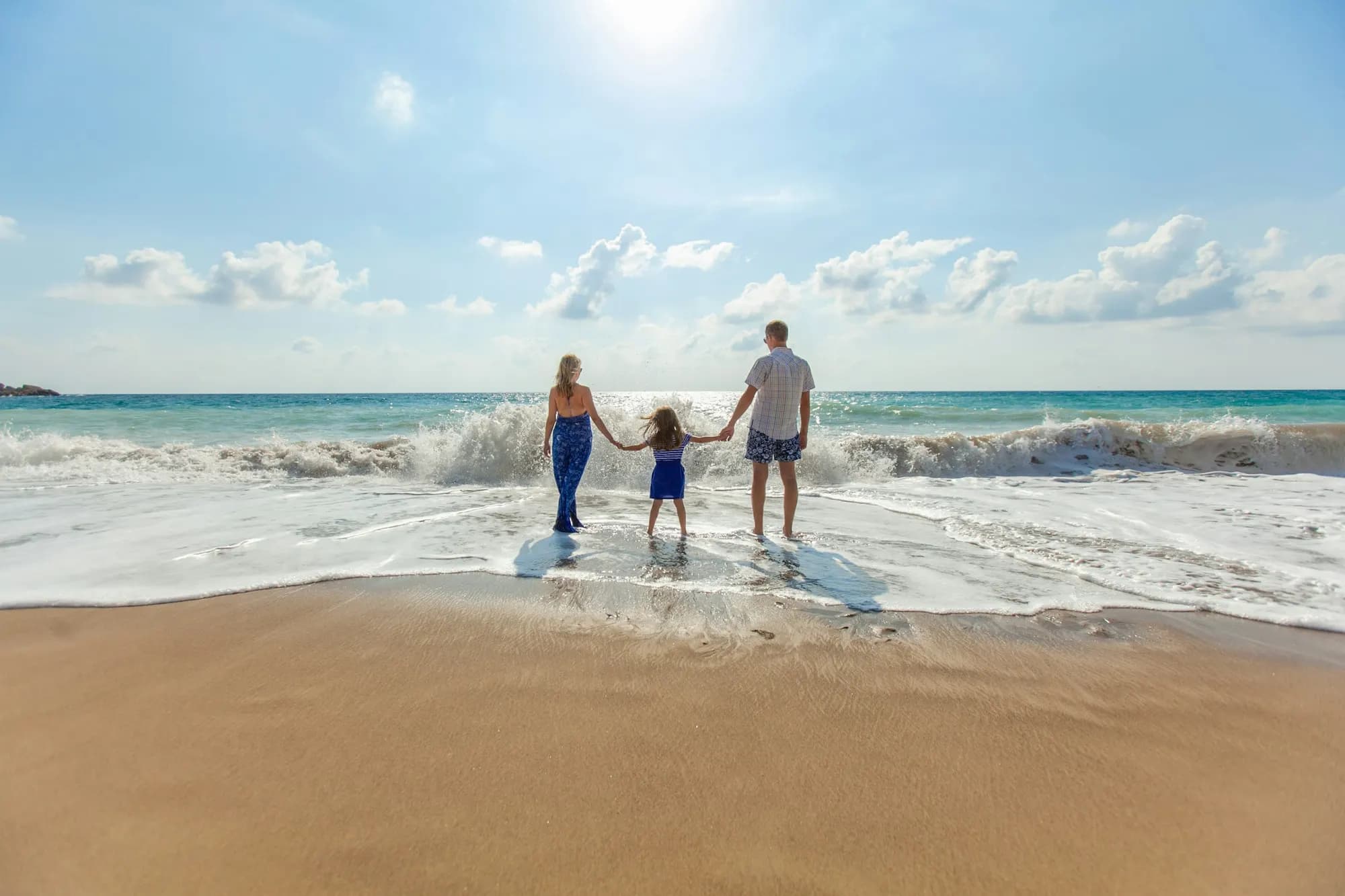 familia caminando de la mano en la orilla del mar