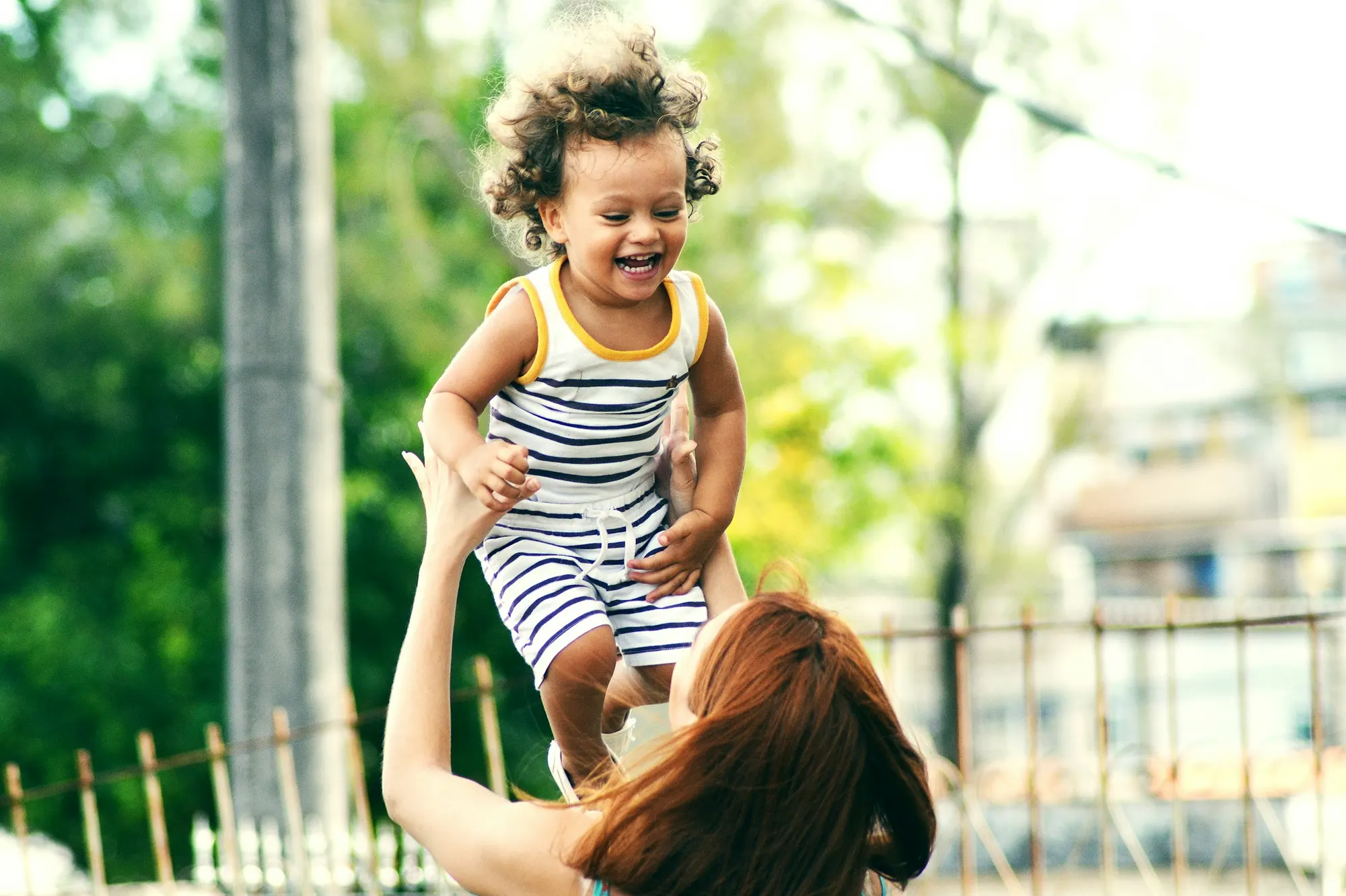 mamá levantando a su hija en el parque