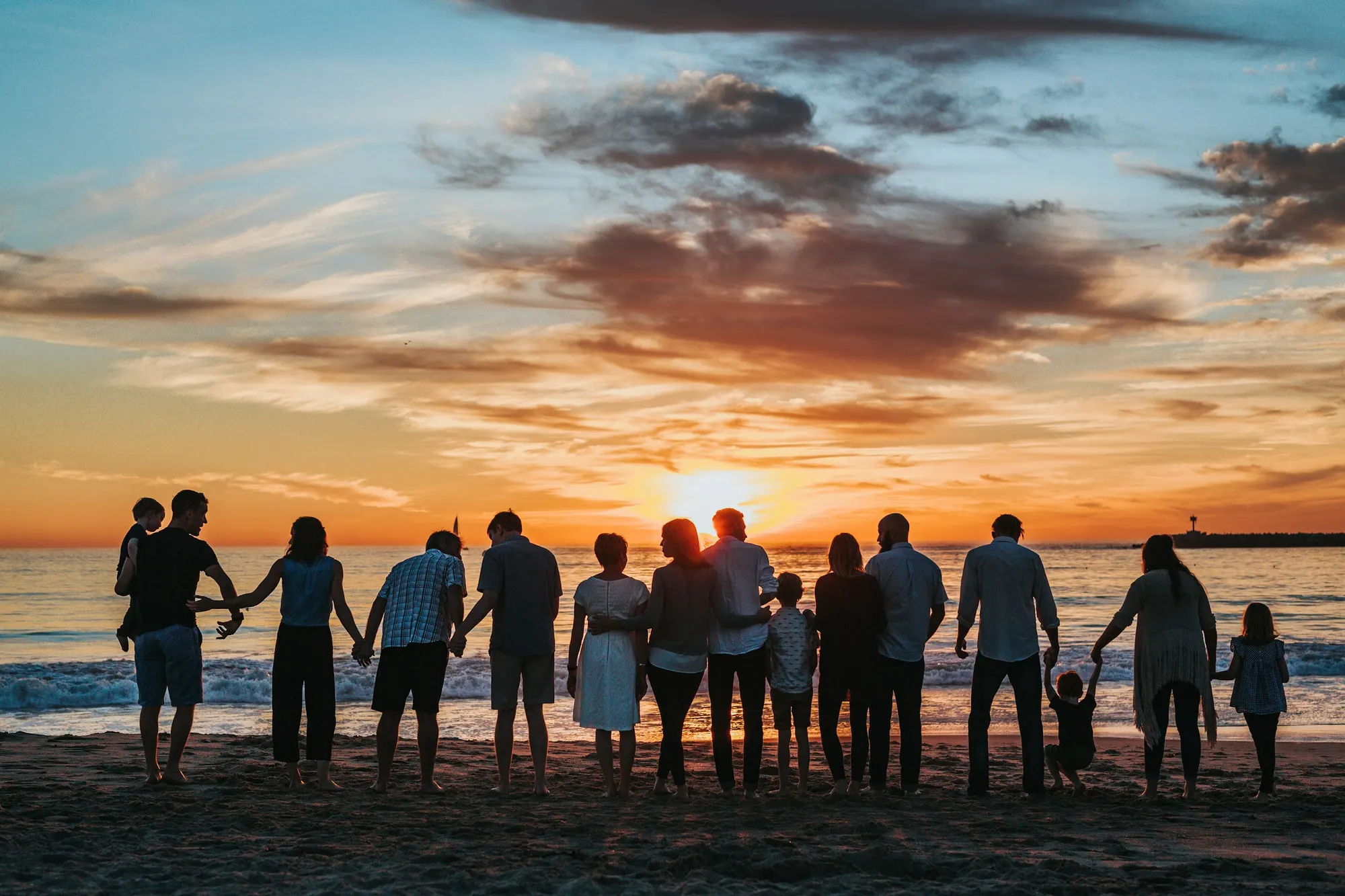 familia grande de espaldas mirando el atardecer en la playa