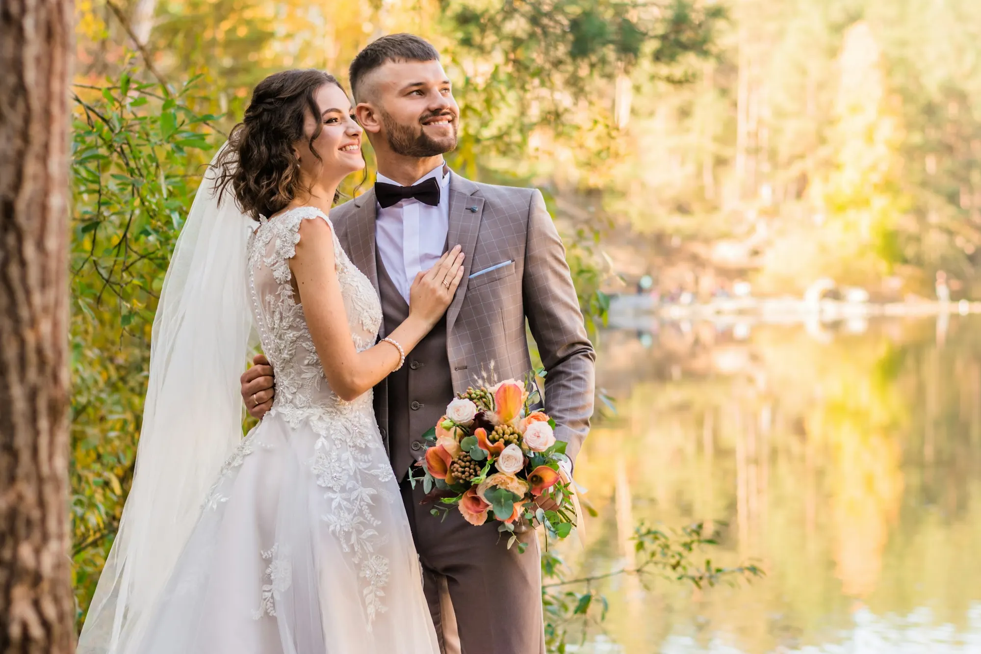 novios abrazados junto a un lago en otoño