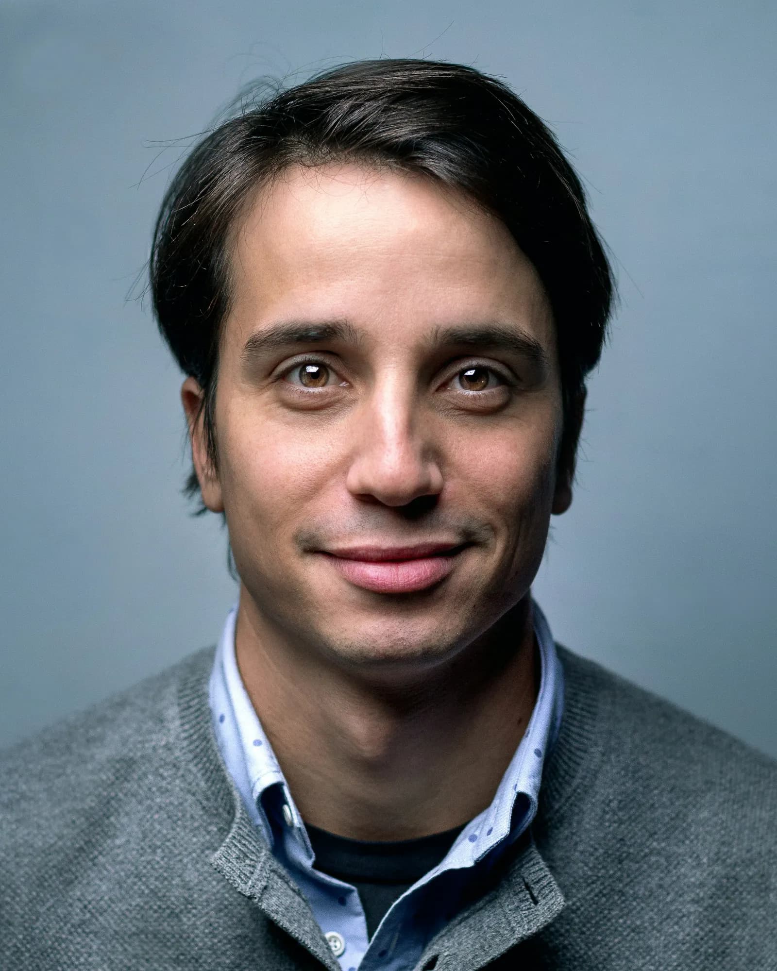 retrato de hombre sonriendo sobre fondo gris