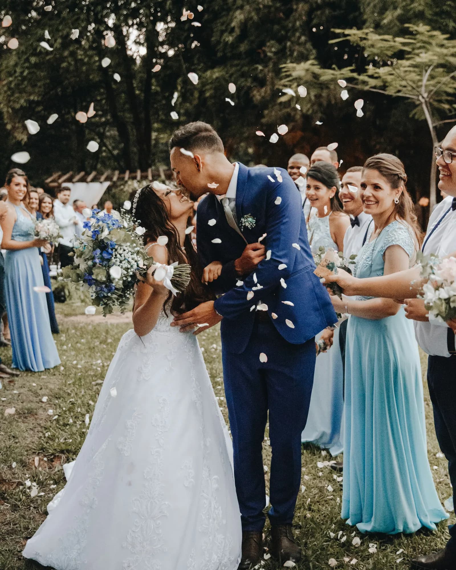 beso de los novios mientras los invitados tiran pétalos