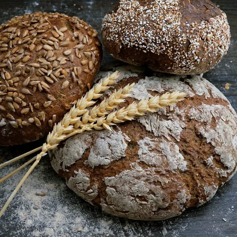 Hogazas de masa madre con semillas y harina, junto a unas espigas de trigo