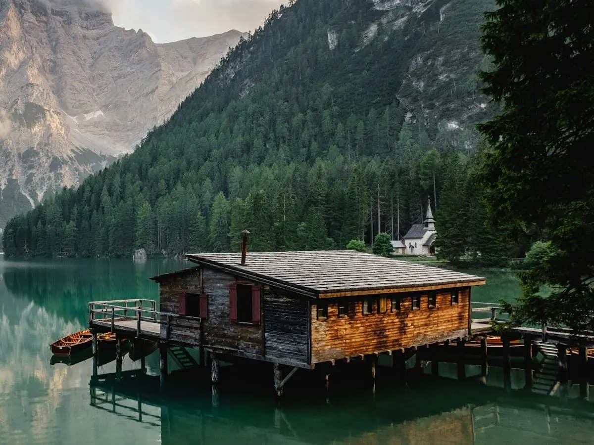 Cabaña La Tala: cabaña de madera con galería y muelle sobre el agua, al pie de un cerro con bosque